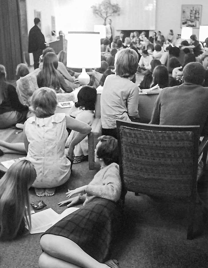 several students sit on the floor during a townhall meeting in the 1960s